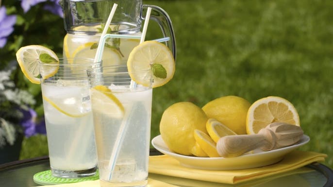 Two glasses of home made iced cold lemonade and pitcher on hot summer. Copyspace