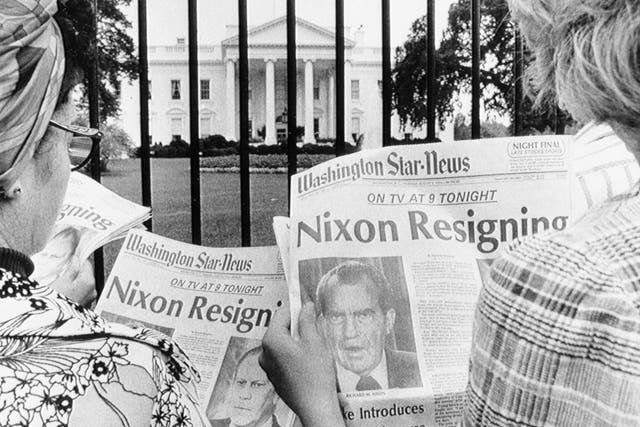 (Original Caption) 8/8/1974-Washington, DC- Newspaper headlines being read by tourists in front of the White House tell of history in the making. It is said to be imminent that President Nixon will become the first President of the country to resign. He will address a nationwide TV audience tonight.