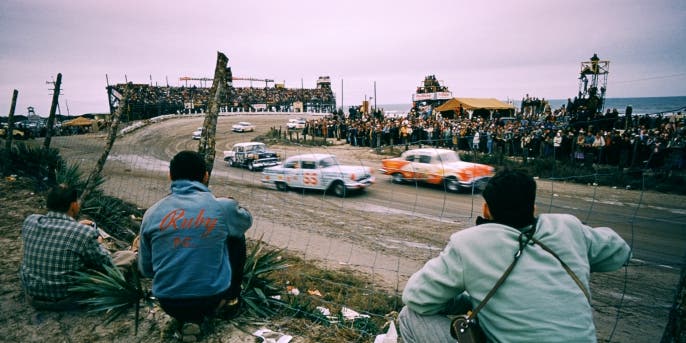 Junior Johnson in the Pontiac #55 car and Charlie Cregar in the Chevrolet #505 car race as fans watch the action at Daytona Beach, 1956. NASCAR has grown from moonshine runners escaping federal agents to one of the most popular sports in the country. (Credit: Hy Peskin/Getty Images)