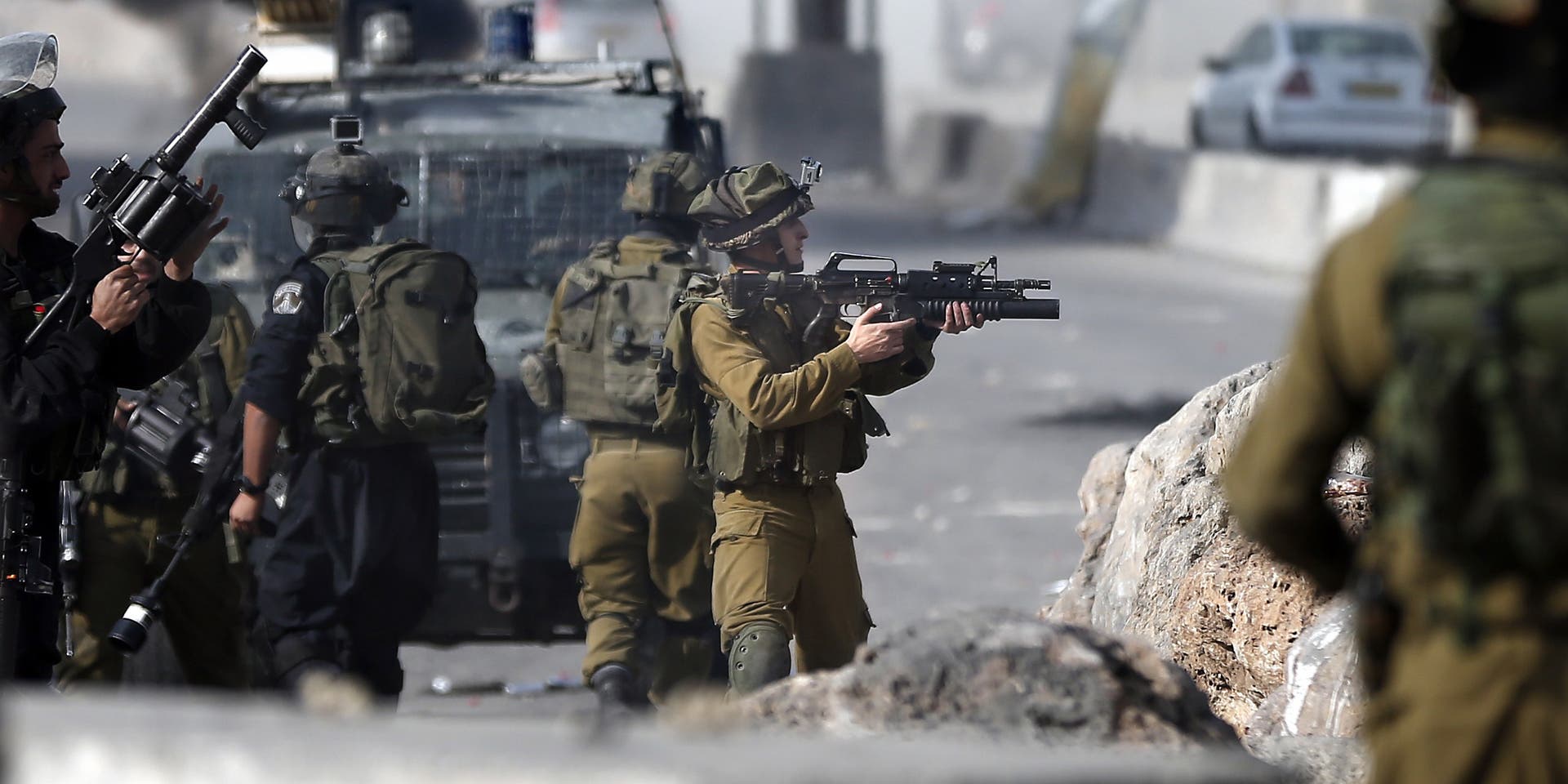 PALESTINIAN-ISRAEL-CONFLICTIsraeli security forces aim their weapons at Palestinian protesters during clashes near the Israeli Qalandia checkpoint, between the West Bank city of Ramallah and Jerusalem, on November 14, 2014, following a demonstration to protest against Israeli authorities allowing settlers to enter the Al-Aqsa mosque compound and Israel imposing restrictions on Muslims wishing to perform Friday prayers at Al-Aqsa Mosque. Israel eased restrictions at Jerusalem's Al-Aqsa mosque after US Secretary of State John Kerry announced agreement on steps to reduce tensions at the flashpoint compound. AFP PHOTO / THOMAS COEX (Photo credit should read THOMAS COEX/AFP via Getty Images)