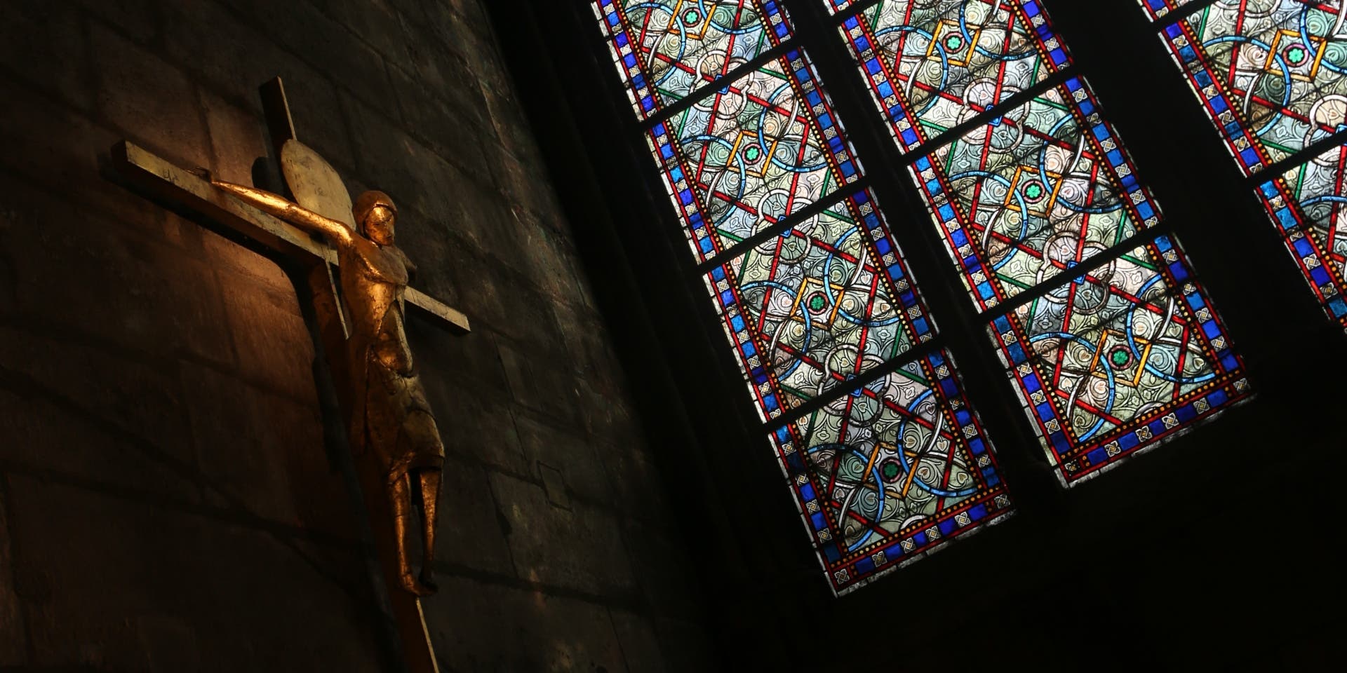 Statue of Jesus Christ on the crucifix by a stained glass window inside Notre-Dame Cathedral, Paris. (Credit: Waring Abbott/Getty Images)
