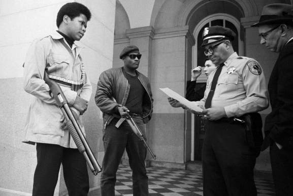 Two members of the Black Panther Party are met on the steps of the State Capitol in Sacramento, May 2, 1967, by Police Lt. Ernest Holloway, who informs them they will be allowed to keep their weapons as long as they cause no trouble and do not disturb the peace.