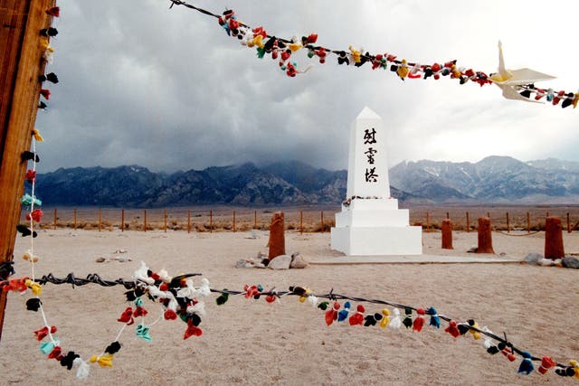 Offerings hanging on the barded wire fence surrounding the cemetery of the Manzanar War Relocation Center in 2000. Manzanarn served as an internment camp for 10,000 Japanese-American citizens and Japanese aliens during World War II after the bombing of Pearl Harbor. The National Park Service maintains Manzanar as a national historic site. (Credit: David McNew/Newsmakers/Getty Images)