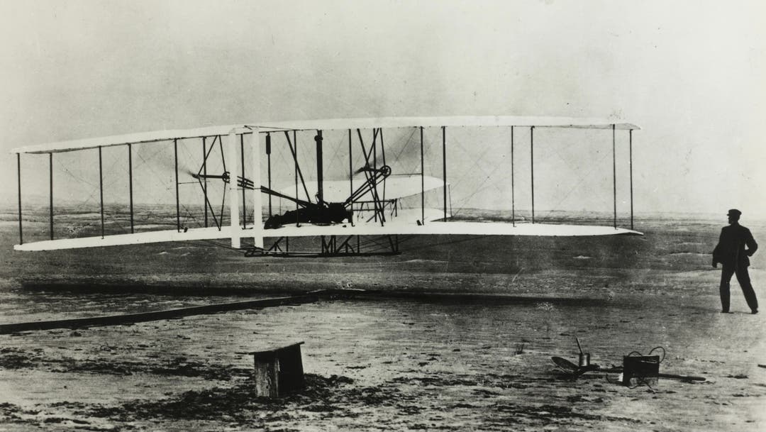 December 17th, 1903, Kittyhawk, North Carolina: The World's first flight with Orville Wright at the controls. His brother Wilbur is running at the side of the machine.