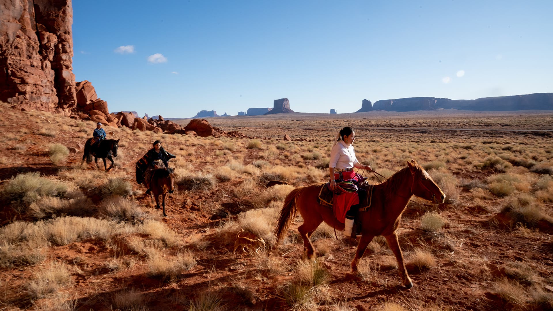A brother and his two sisters riding their horses on Navajo land on the tribal park in the desert area of Monument Valley, Arizona.