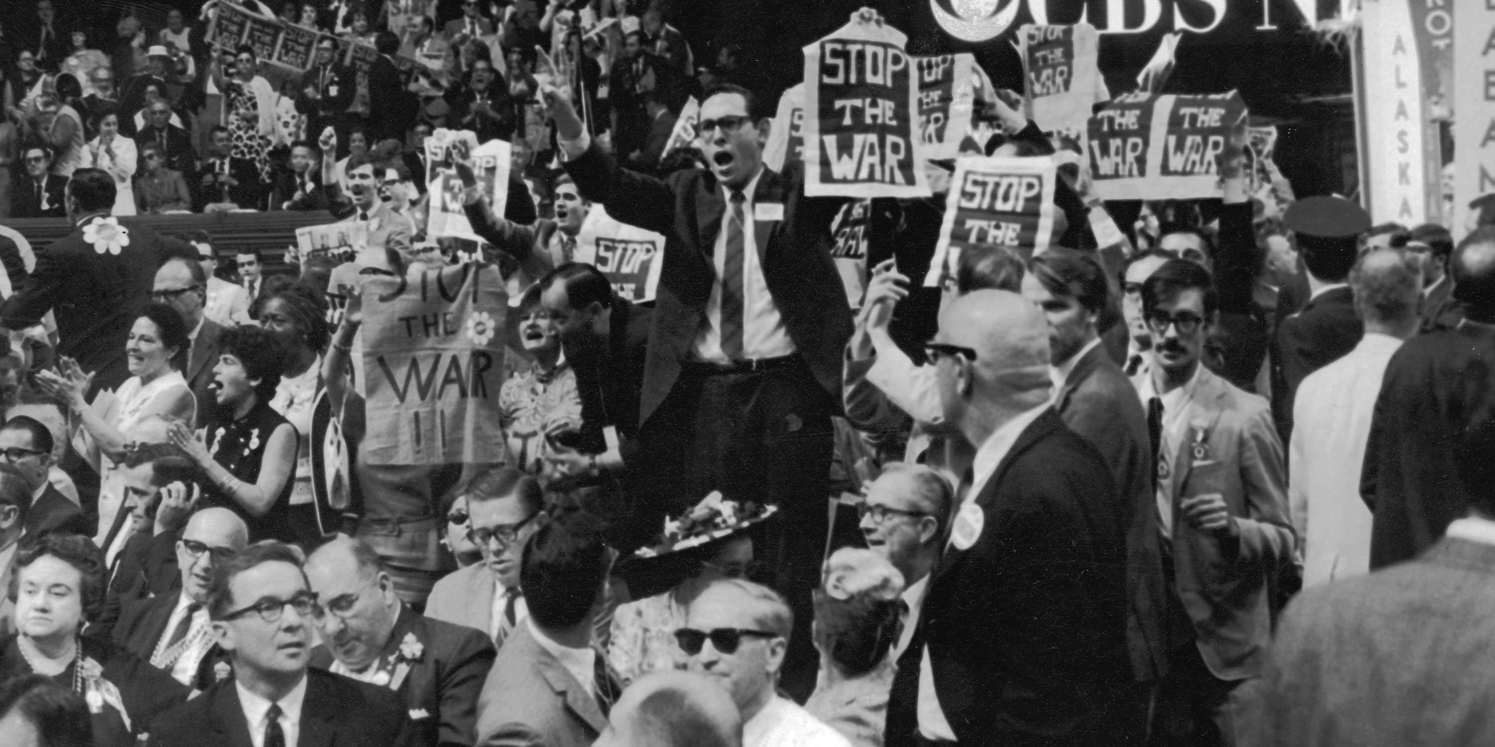 A crowd of delegates in the 1968 Democratic Convention convention holding up the signs that say Stop the War